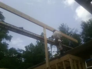 Carpenter setting a ridge beam over a new addition frame — Ice Dam Removal by Roofing Brothers in Clintondale