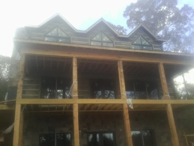 Dormers and porch framing on a large log home under construction — Roof Coating work by our crew in Clintondale