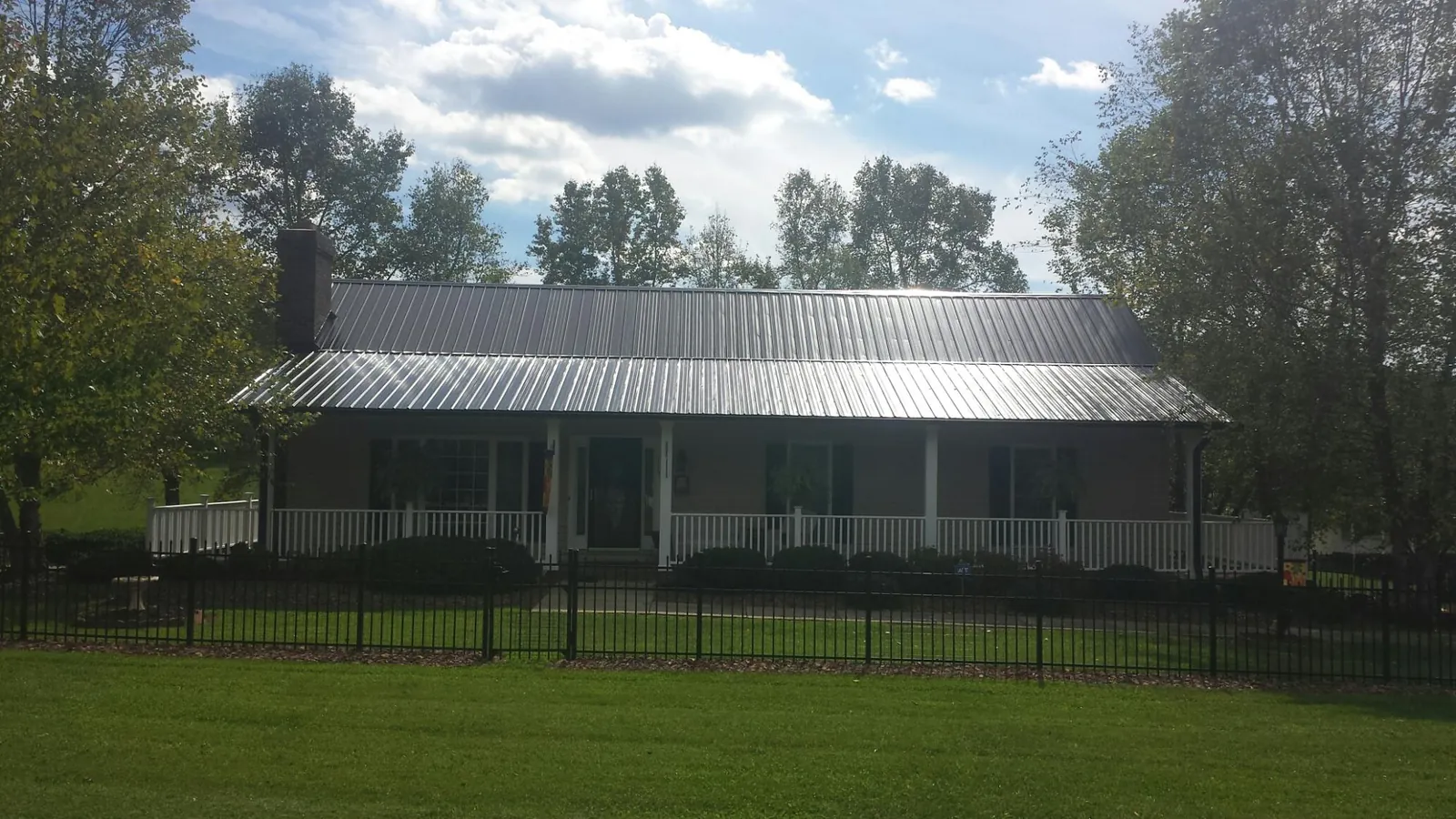 Gray metal roof on a brick ranch with a full width front porch — Gutter Guard Installation work by our crew in Clintondale