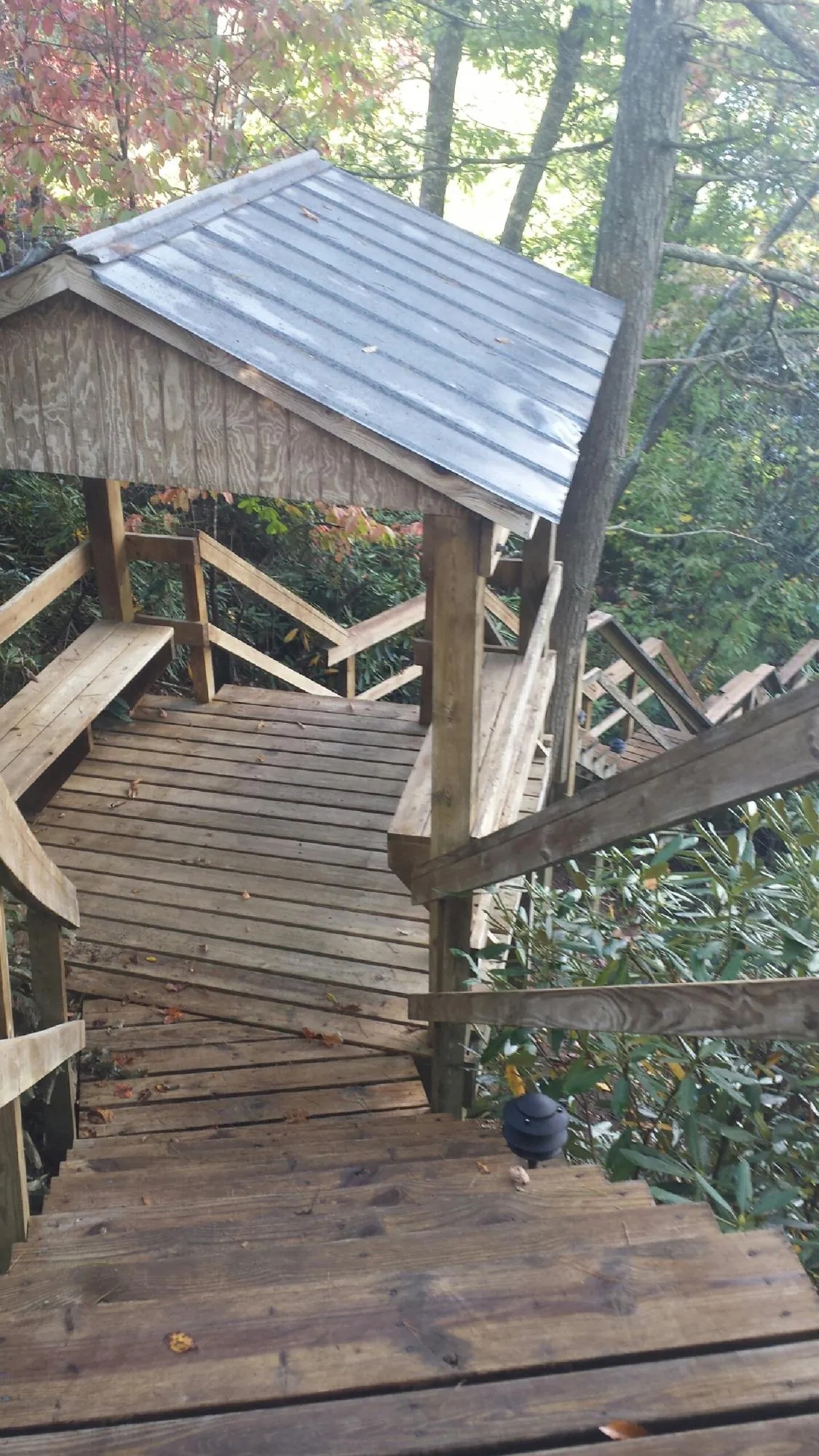 Metal roofed shelter over wooden steps on a wooded walkway — Skylight Repair & Installation work by our crew in Clintondale
