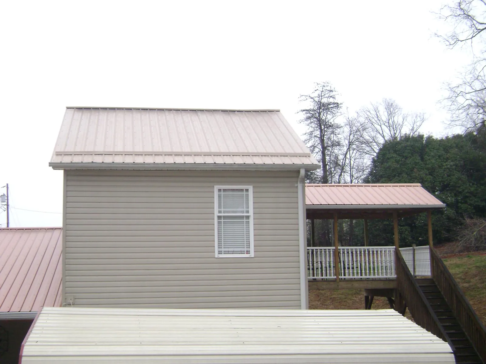 Tan metal roofs on a two story addition and attached porch, from a Roof Replacement job in Clintondale