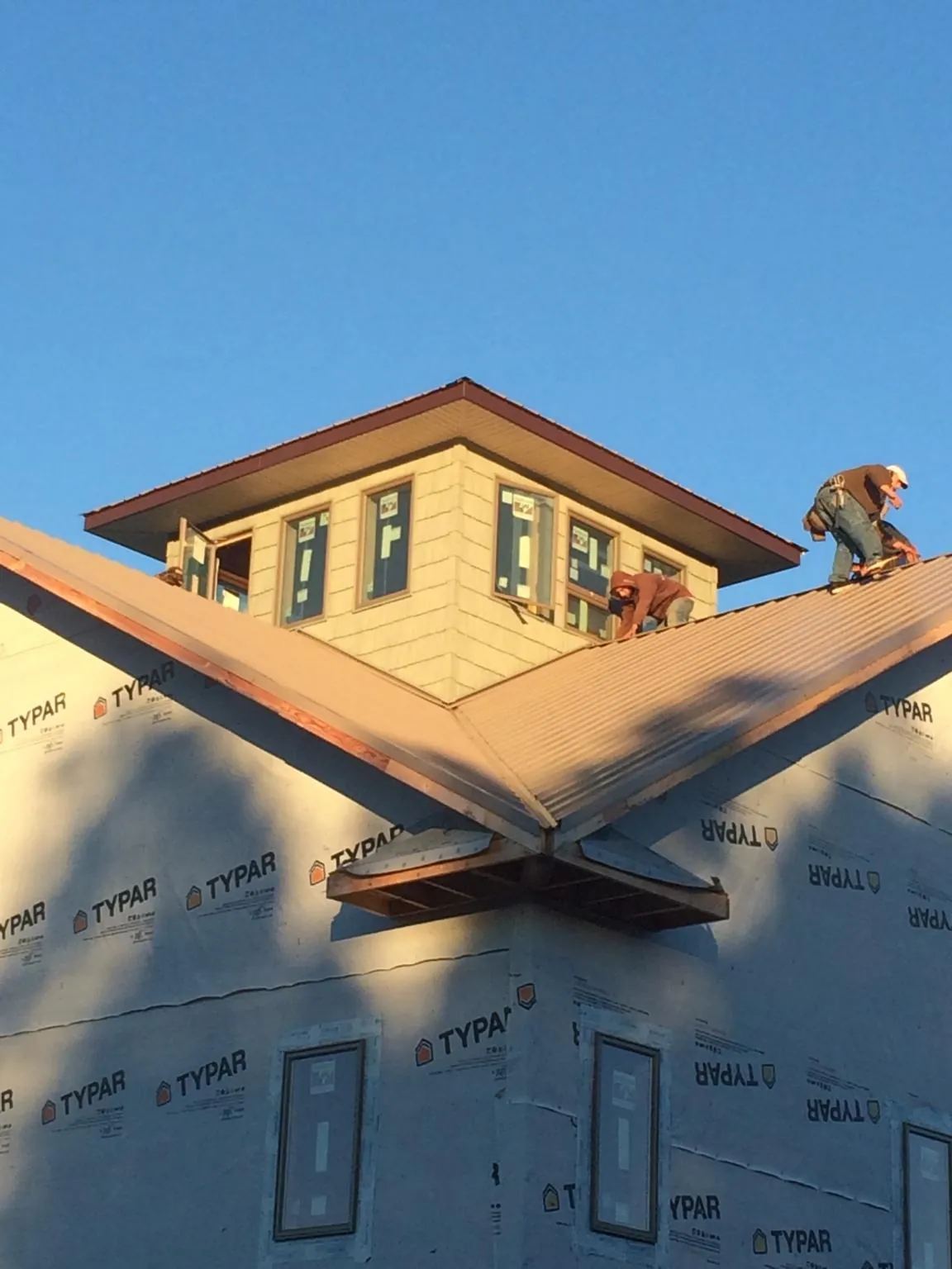 Roofers working around a rooftop cupola on a new metal roof at sunset — Roof Waterproofing in Clintondale by Roofing Brothers
